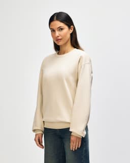 A beige Gildan Softstyle adult sweatshirt is displayed on a model, with a plain design and a visible logo.