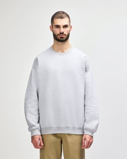 A grey Gildan Softstyle adult sweatshirt worn by a model, featuring a round neckline and long sleeves.