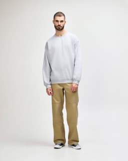 A grey Gildan Softstyle adult sweatshirt worn by a man, paired with khaki trousers and black shoes, standing on a plain background.