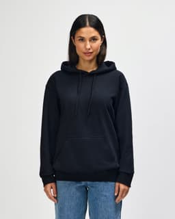 A black hooded sweatshirt worn by a model with a front pouch pocket and drawstring hood. Features a logo.