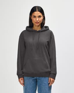 A hooded sweatshirt in khaki green, featuring a front pocket and a logo, worn by a model.