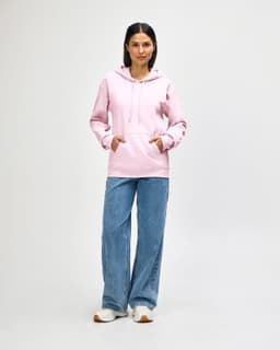 A pink Gildan Softstyle adult hooded sweatshirt worn by a model with blue jeans and white shoes, featuring a logo.