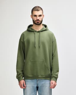 A woman wearing a green hooded sweatshirt with a front pocket and drawstring, standing against a plain background.