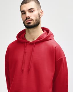 A red hooded sweatshirt is worn by a woman, featuring a drawstring hood and a relaxed fit.