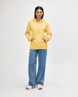 A yellow hooded sweatshirt worn by a model, paired with black jeans and sneakers, featuring a logo.