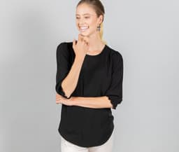 A black blouse with shirred cuffs, featuring a relaxed fit and a rounded neckline, worn by a smiling model.