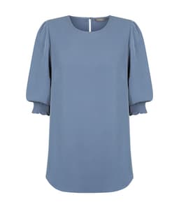 A blue blouse with shirred cuffs and a round neckline, featuring a subtle back opening and branding logo.