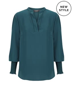A teal long sleeve top features a mandarin collar and smocked sleeves, complemented by a logo.