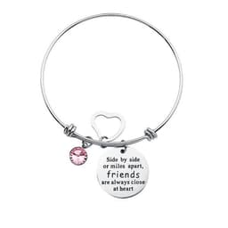 A silver adjustable charm bangle bracelet featuring a round charm and a pink gemstone. It has a heart-shaped clasp.