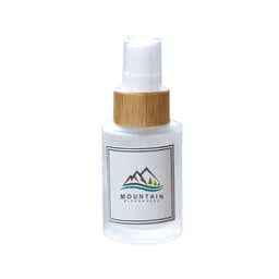 A frosted glass spray bottle with a white and bamboo cap, featuring a logo.