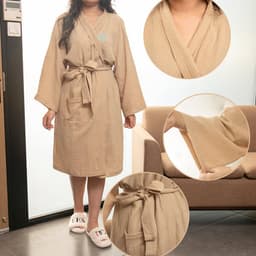 A long cotton bathrobe in a soft beige colour, featuring a belt and pockets, displayed on a model.