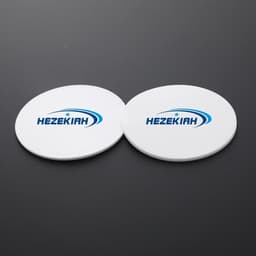 Two round white PVC soft rubber coasters with a logo.