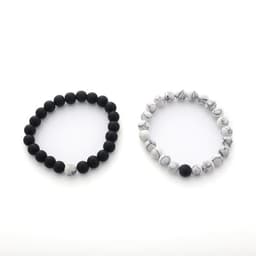 A pair of bracelets featuring black lava stones and white marbled stones, each with a smooth design and an understated style.