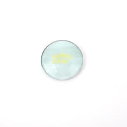 A round crystal glass fridge magnet in light green with a logo on the surface.