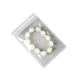 A clear PVC jewellery seal bag containing a pale green bracelet with metal accents. The bag has a ziplock closure.