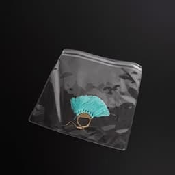A transparent pouch containing a gold ring adorned with a turquoise tassel, set against a black background.