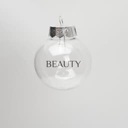 A clear plastic ball ornament with a silver cap and the word "BEAUTY" printed on it.