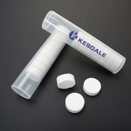 A clear tube containing compressed white face towels, with several towels outside the tube. The tube has a logo.