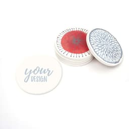 A set of absorbent ceramic coasters in white, featuring various designs in blue and red, with a cork base.