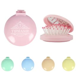 A pink plastic folding massage comb with a mirror, featuring a branded logo, alongside other coloured options.
