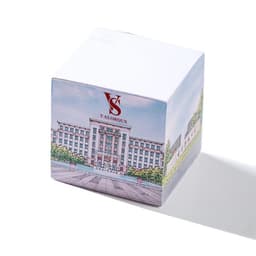 A white sticky note cube featuring an illustrated building on one side and a logo on top. 