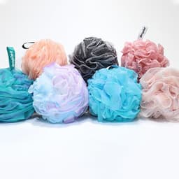 Collection of flower-shaped shower balls in various pastel colours, including blue, pink, and black, with tags.