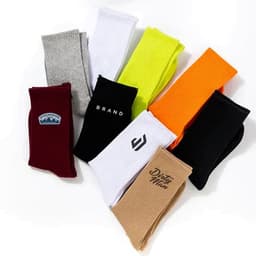 Custom combed cotton sports socks in various colours, including grey, white, orange, black, and maroon, featuring different logos.