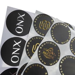 A collection of circular, custom hot stamping stickers in black and gold, featuring various logos and designs.