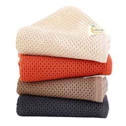 Four textured face towels stacked, in cream, burnt orange, taupe, and charcoal colours, featuring a logo on one towel.