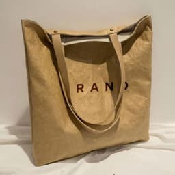 A beige washable kraft paper shoulder bag with a logo and long handles.