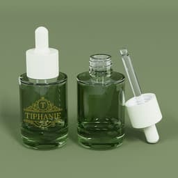 A green glass bottle with a dropper, featuring a white lid and a logo, alongside an empty glass bottle.