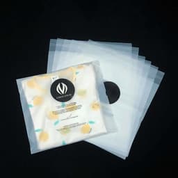 A set of clear biodegradable self-sealing garment bags containing a folded shirt with a lemon pattern.