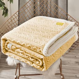 A folded winter quilt cover in soft yellow with a textured pattern and white trim, resting on a chair.