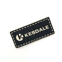 A black custom PU leather label with a stitched border and a logo. It features the text "KESDALE" in white.