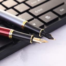 A custom fountain pen in silver and red, featuring gold trim, positioned alongside a black keyboard.