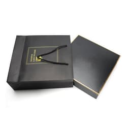 A black gift box set with a gold-trimmed lid, accompanied by a black shopping bag featuring a logo.
