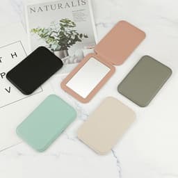 A set of PU folding makeup mirrors in black, pink, grey, mint green, and beige, displayed on a marble surface.