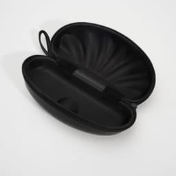 A shell-shaped black EVA glasses case with a textured exterior and a smooth, spacious interior.