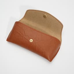 A brown sunglasses case with a button closure, featuring a soft interior lining. The case is opened, displaying its interior.