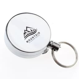 A circular silver retractable badge holder with a keyring attachment and a logo featuring mountains.