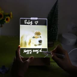 A light-up panel featuring a dog image, personalised text, and held in a hand. The panel is clear with a wooden base.