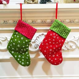 Two Christmas stocking-shaped gift bags in green and red, adorned with white snowflakes and bright fabric tops.