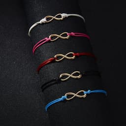 A set of braided infinity-shaped bracelets in white, pink, red, black, and blue, featuring gold-coloured symbols.
