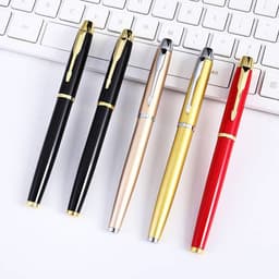 A ballpoint pen set featuring black, gold, silver, red, and a metallic pen, alongside a keyboard.