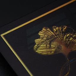 A holographic rainbow business card featuring a decorative gold leaf design on a dark background.