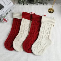 Four large cable knitted Christmas stockings in red and cream, featuring a textured design and ribbed tops.