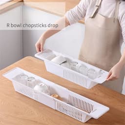 A multifunctional white bathroom bathtub tray with compartments holding glasses, bowls, and utensils. It features a logo.