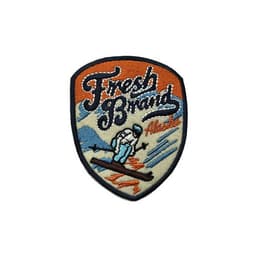 A custom embroidery patch featuring a snowy mountain scene with a skier, predominantly in blue, orange, and beige.