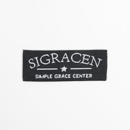 A black woven sewing label featuring white embroidered text and a star design.
