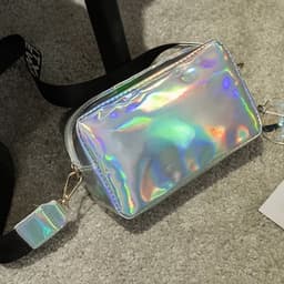 A small holographic crossbody bag with a shiny, reflective surface and a black strap.